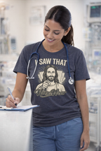 Nurse wearing dark heather I Saw That graphic tee at nurses station with blue scrubs, stethoscope, and clipboard