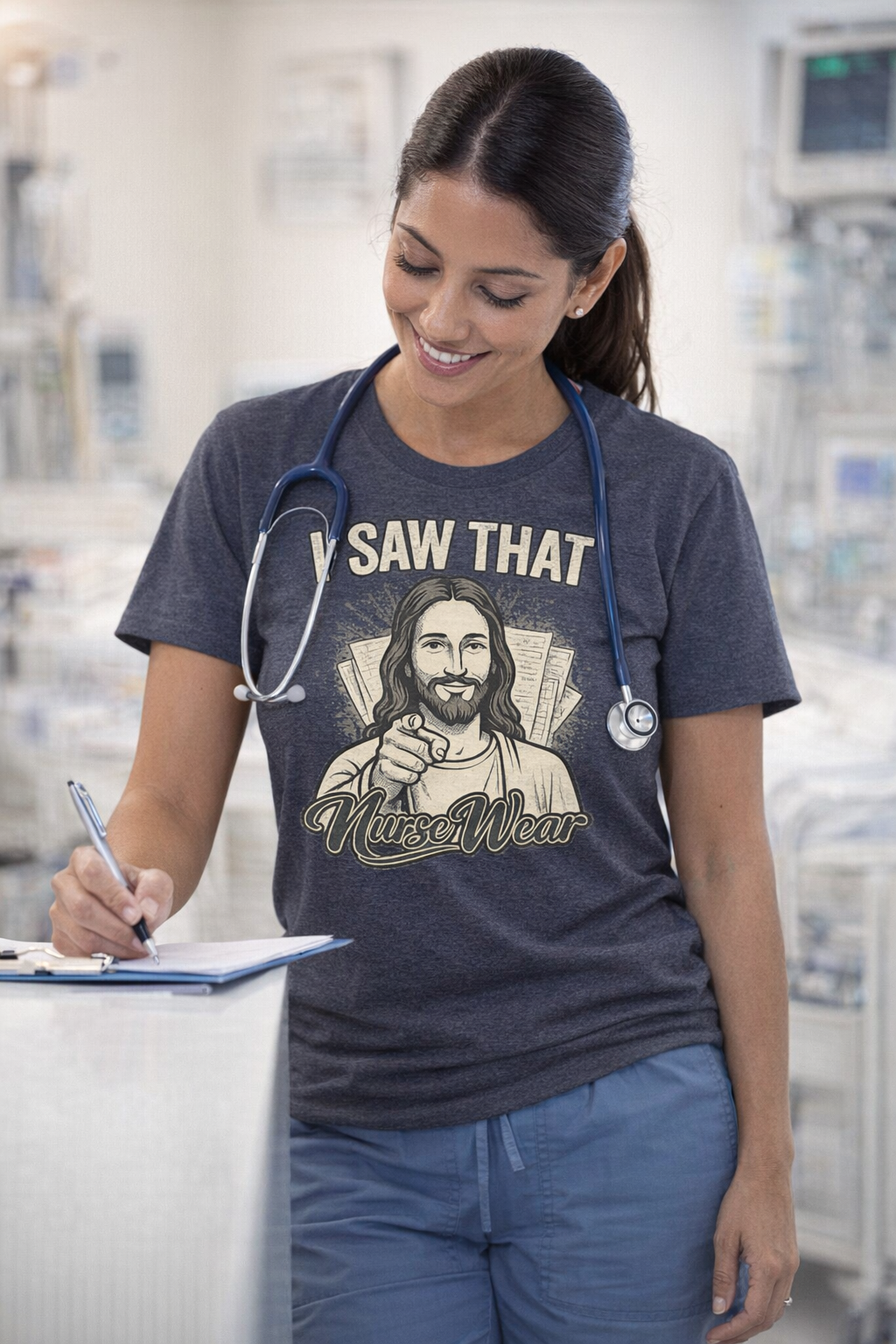 Nurse wearing dark heather I Saw That graphic tee at nurses station with blue scrubs, stethoscope, and clipboard