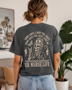 Person wearing a dark gray t-shirt with a graphic design and text, standing in a room with plants and decor.