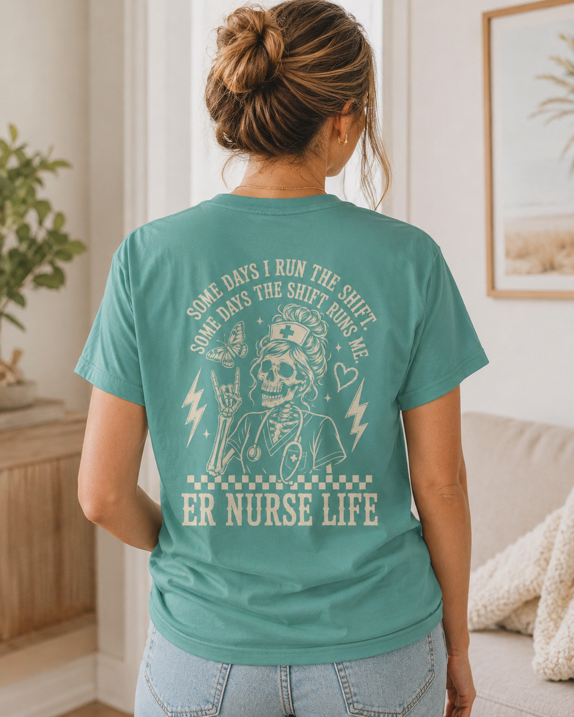 Person wearing a teal t-shirt with a graphic and text in a living room.
