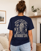 Person wearing a navy blue t-shirt with a skeleton nurse design and text in a living room.